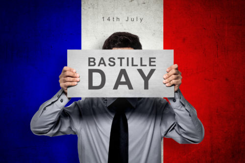 「バスティーユデイ」のプラカードを持つ男性とフランス国旗