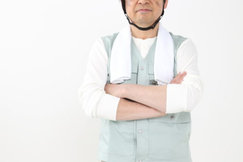 腕組みをする作業着の男性