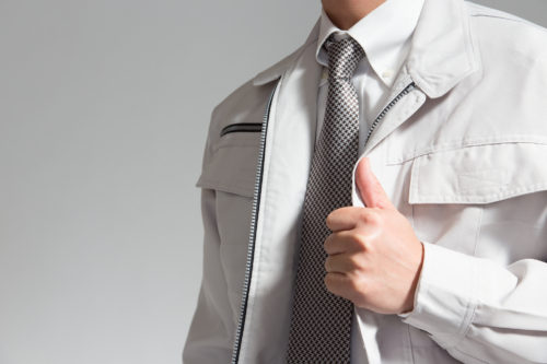 サムズアップする作業着の男性