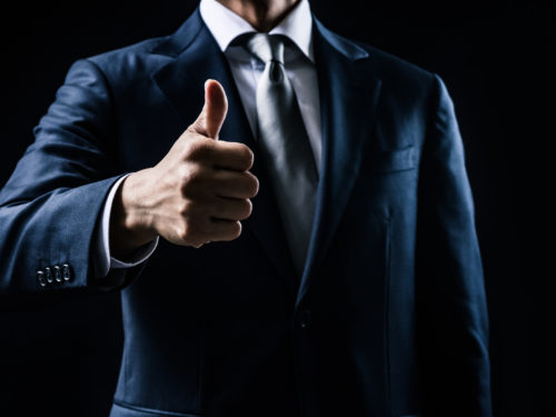 サムズアップするスーツの男性
